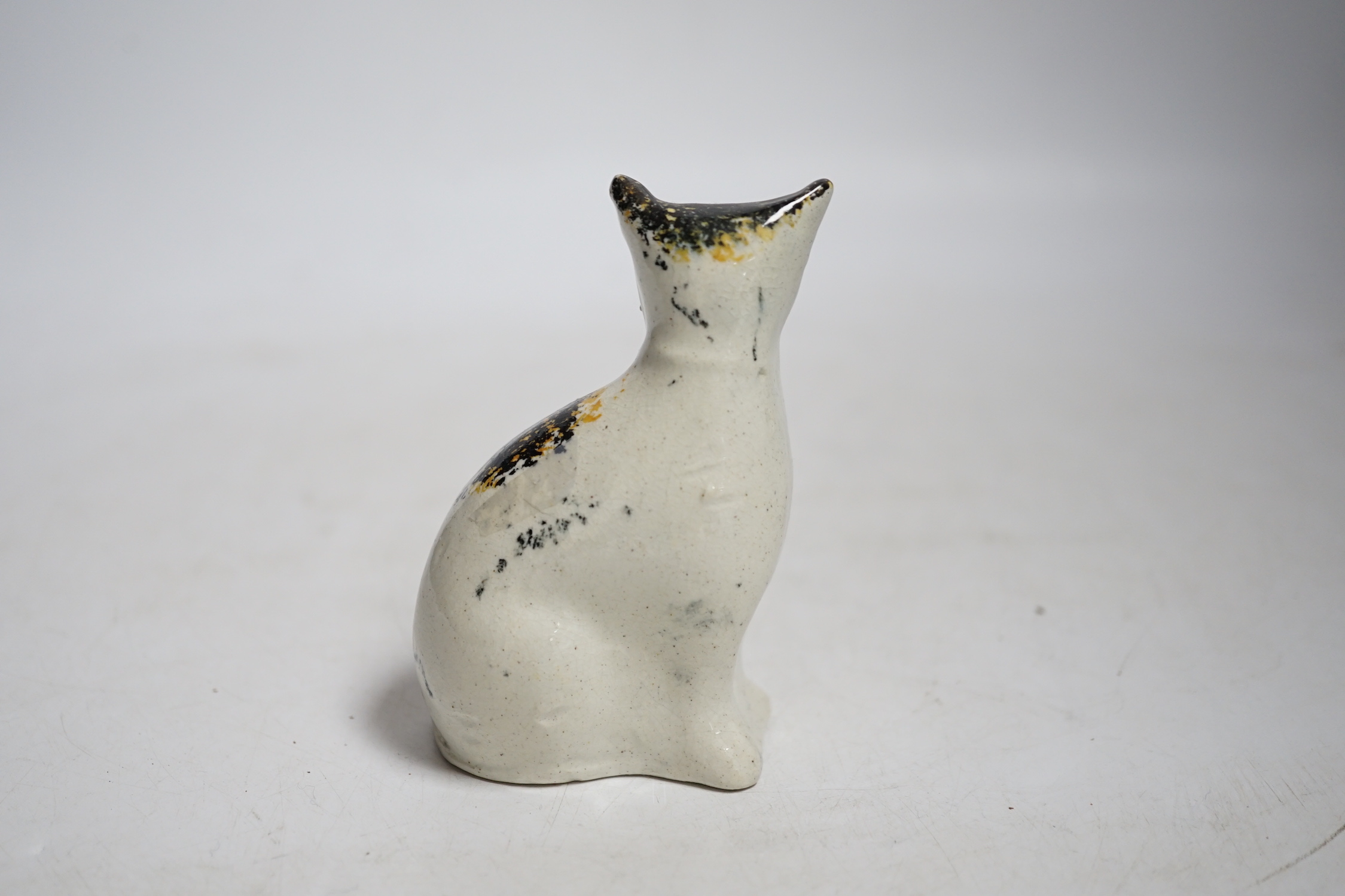 A Staffordshire pottery cat with yellow collar, mid 19th century, height 9.5cm